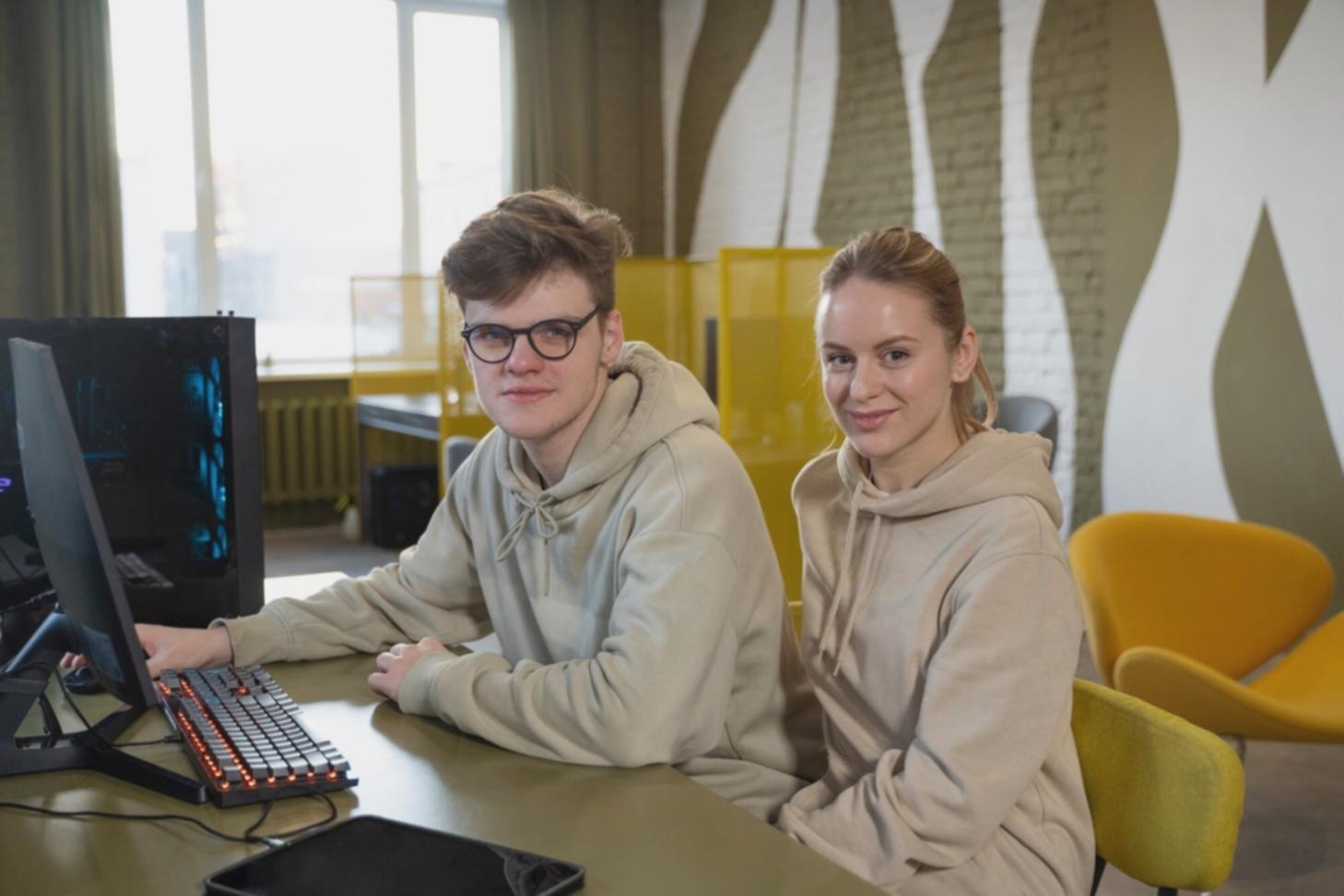 Estudantes desenvolvendo jogos em laboratório moderno com múltiplas telas